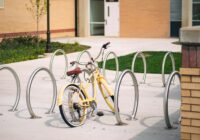 a yellow bike parked next to a metal pole