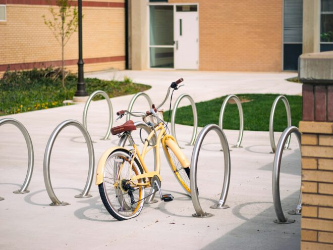 a yellow bike parked next to a metal pole