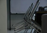 Empty chairs sit in a dimly lit classroom.