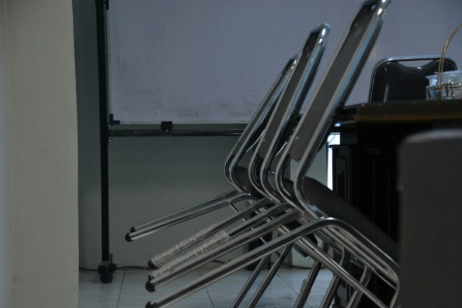 Empty chairs sit in a dimly lit classroom.